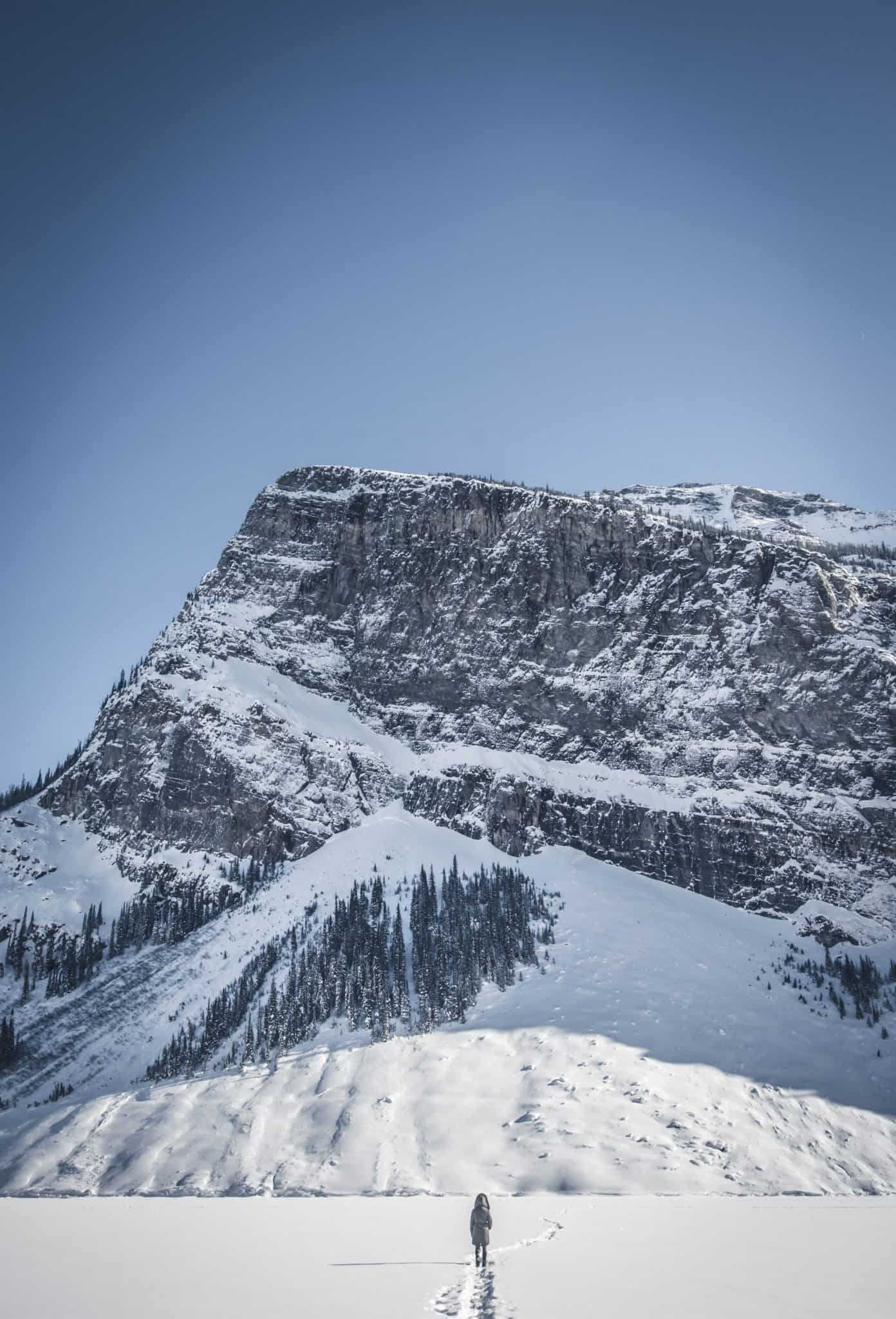 Natasha Stands On A Frozen Lake Louise Looking Up At Fairview Mountain