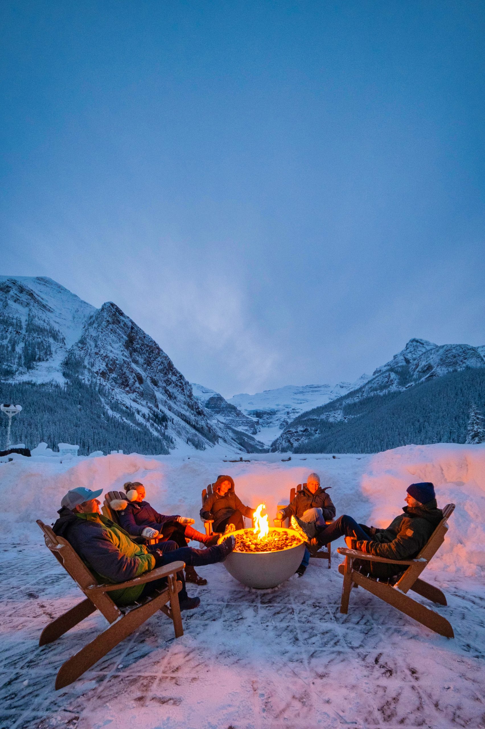 The Seagle Family Sits Around A Fire At Lake Louise In Winter