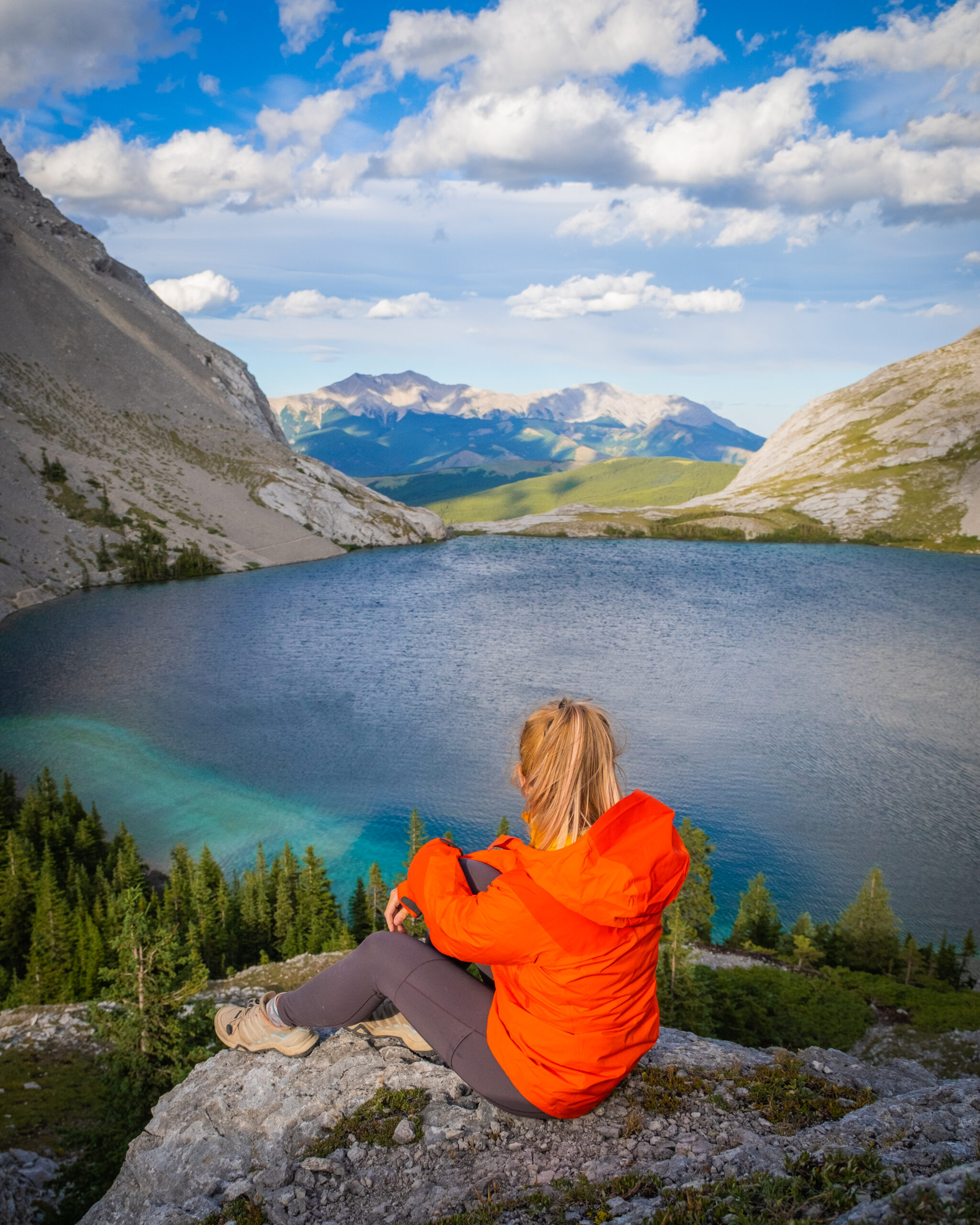 Natasha Sits Above Carnarvon Lake In An Orange Jacket