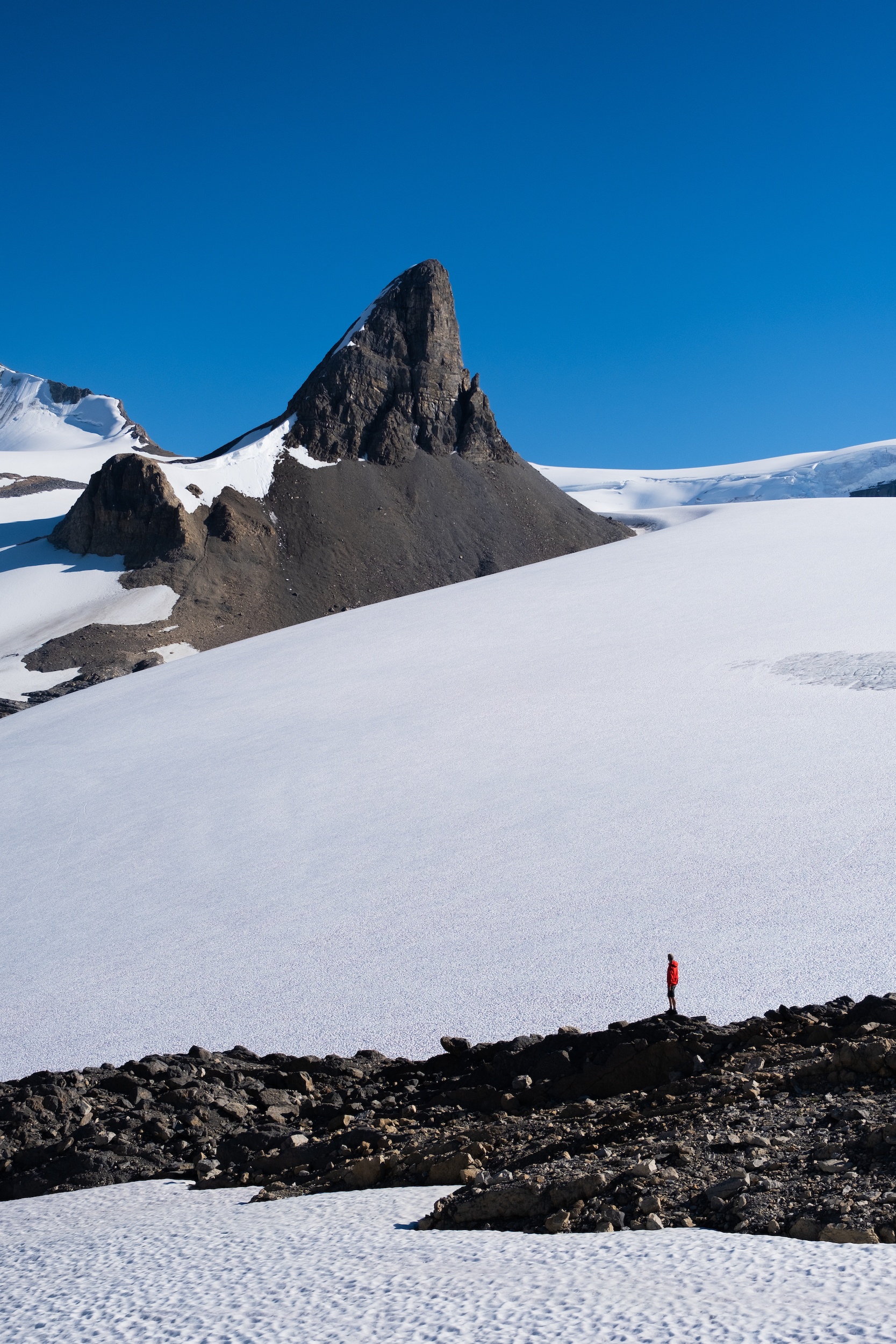 Cameron Stands Along Columbia Icefield On Rocky Outcropping surrounded by glaciers