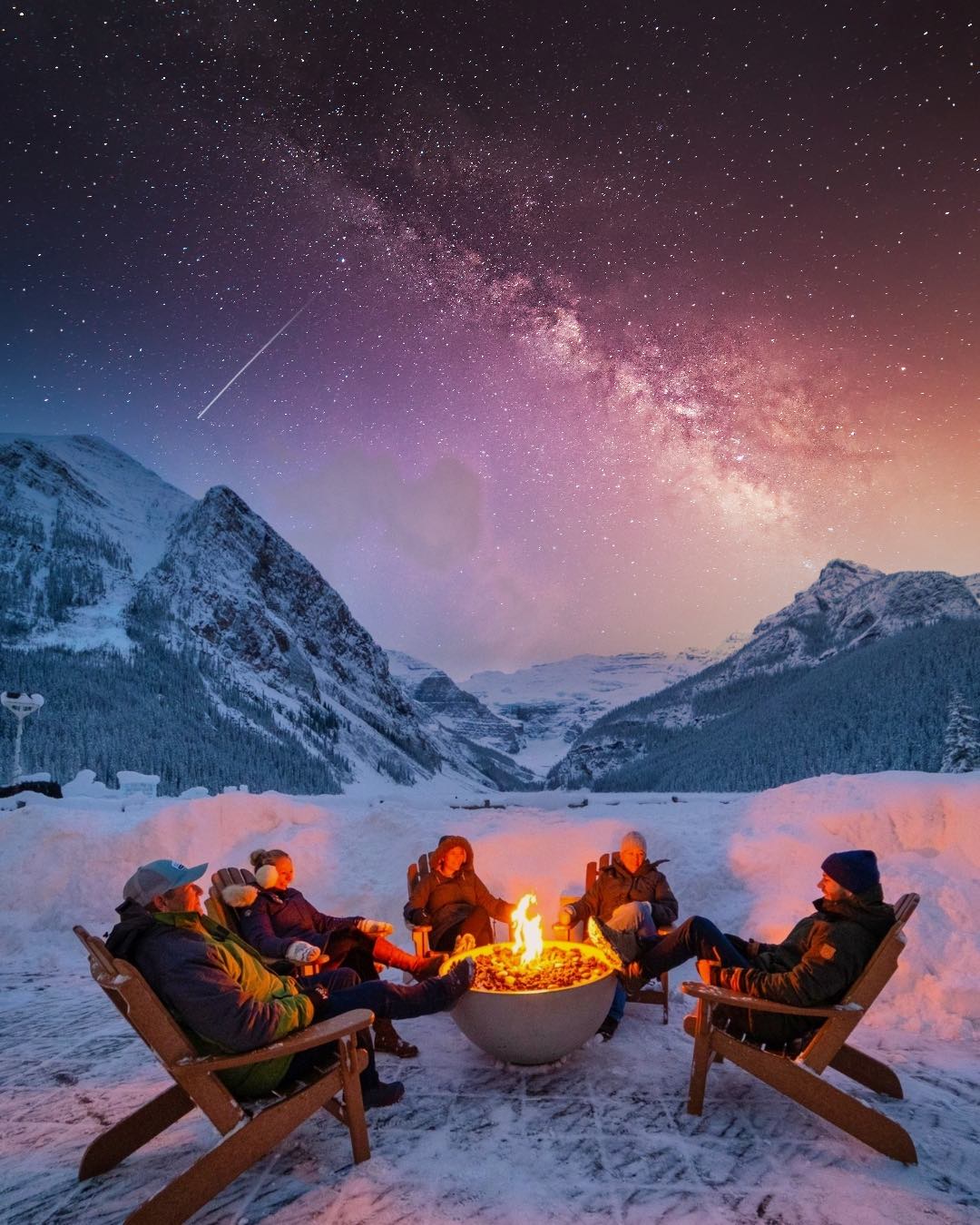 The Family Sits Around A Fire At Lake Louise In The Winter