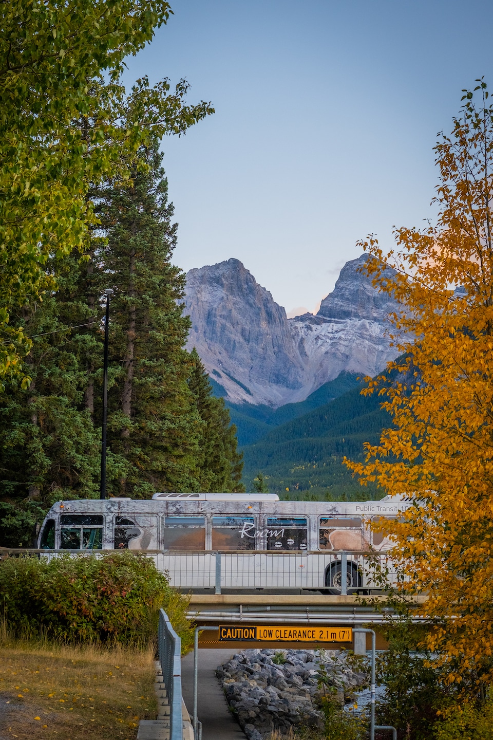 Roam Transit Bus Driving Over A Bridge In Canmore