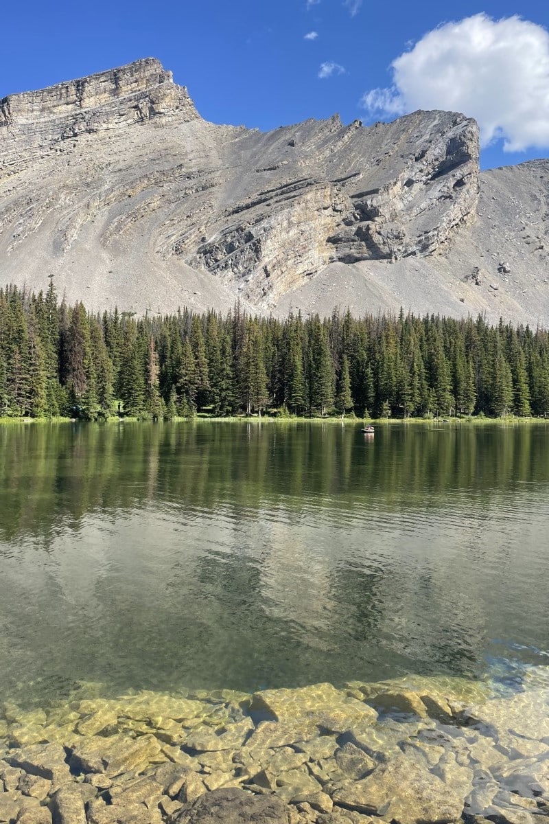 angler in a float on the first picklejar lake with trees and mountains in the background