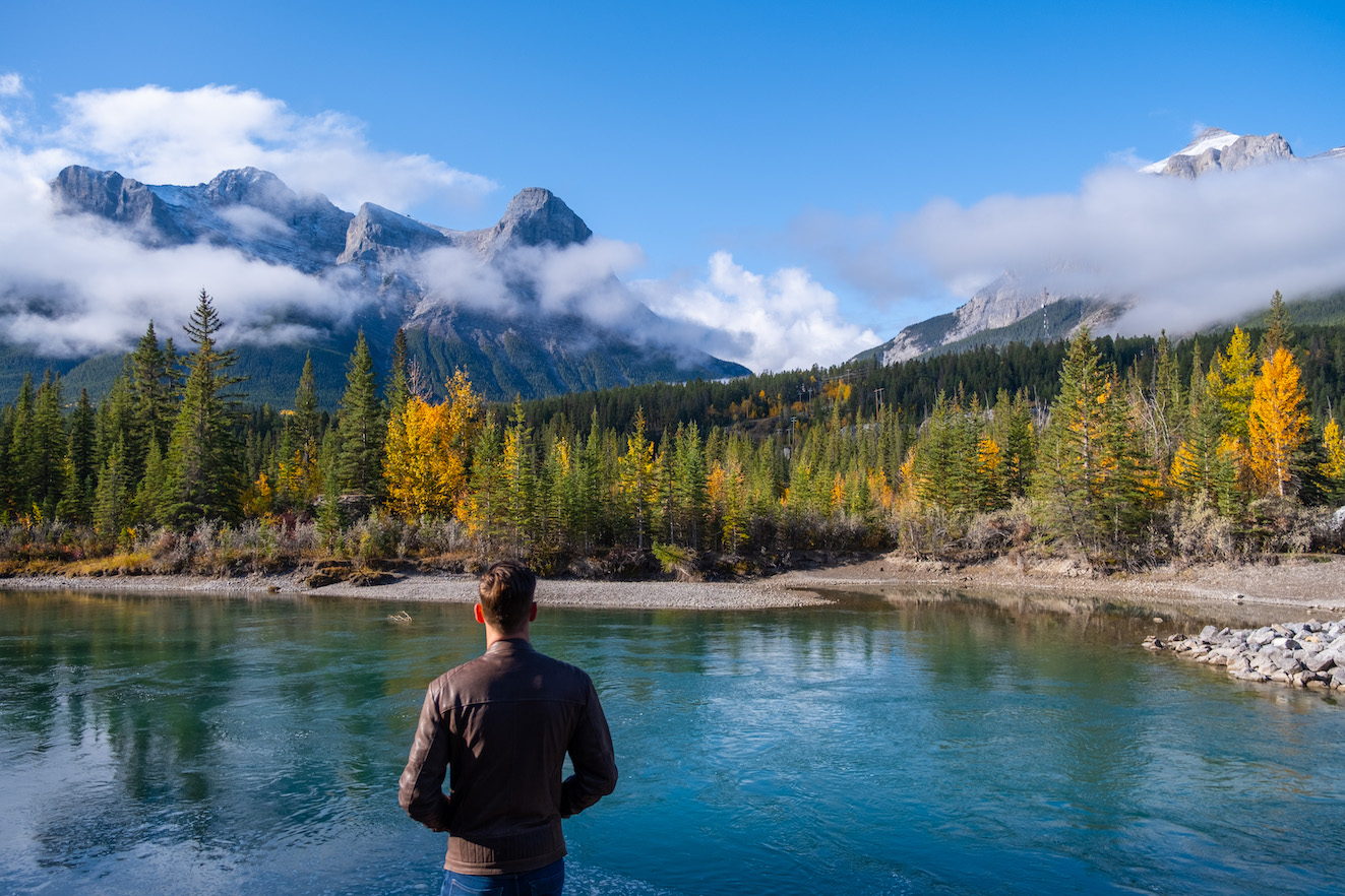Cameron Stands Along The Bow River In Canmore In September Wearing Leather Jacket
