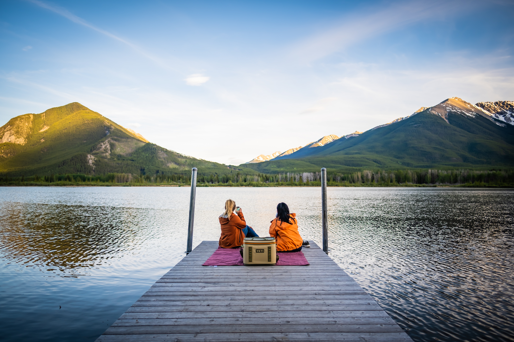 Natasha And Teresa Sit Along Vermilion Lakes In Banff At Sunset